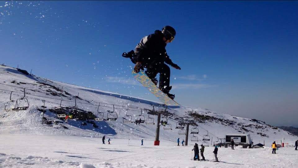 Rider de snowboard saltando sobre la nieve en Sierra Nevada