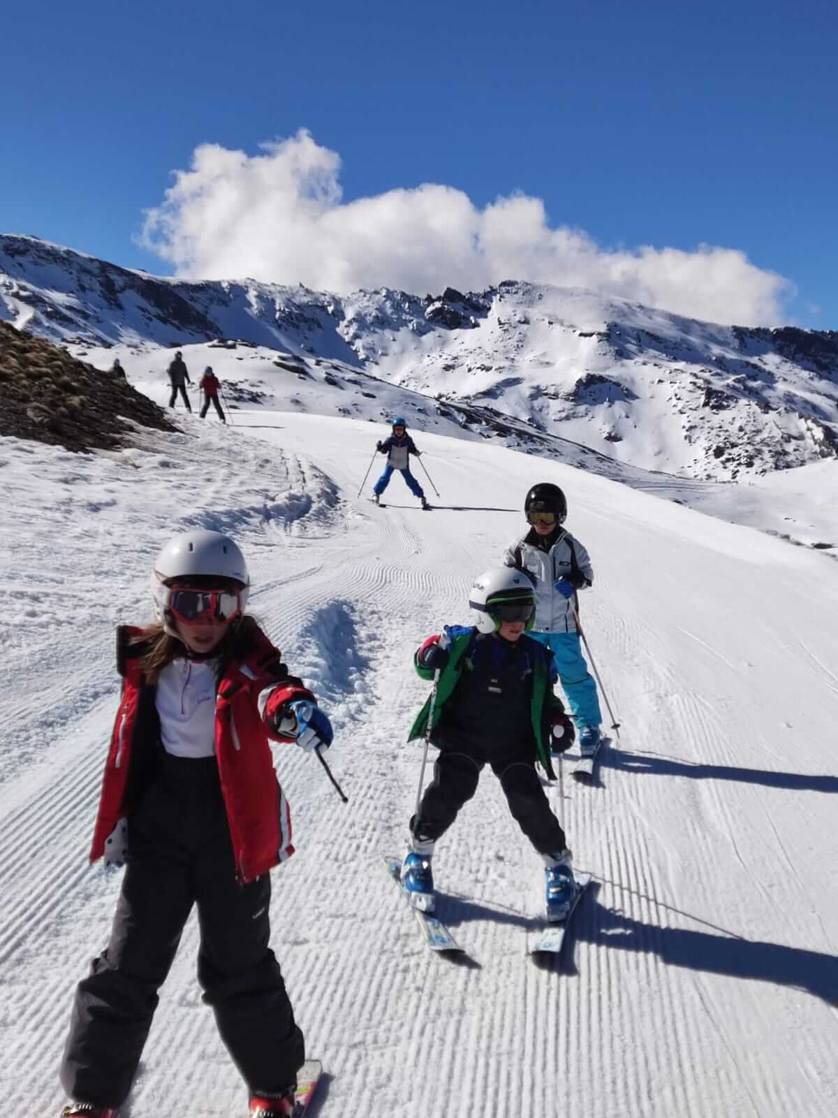 Niños esquiando por una pista de Sierra Nevada en una clase de Ski School