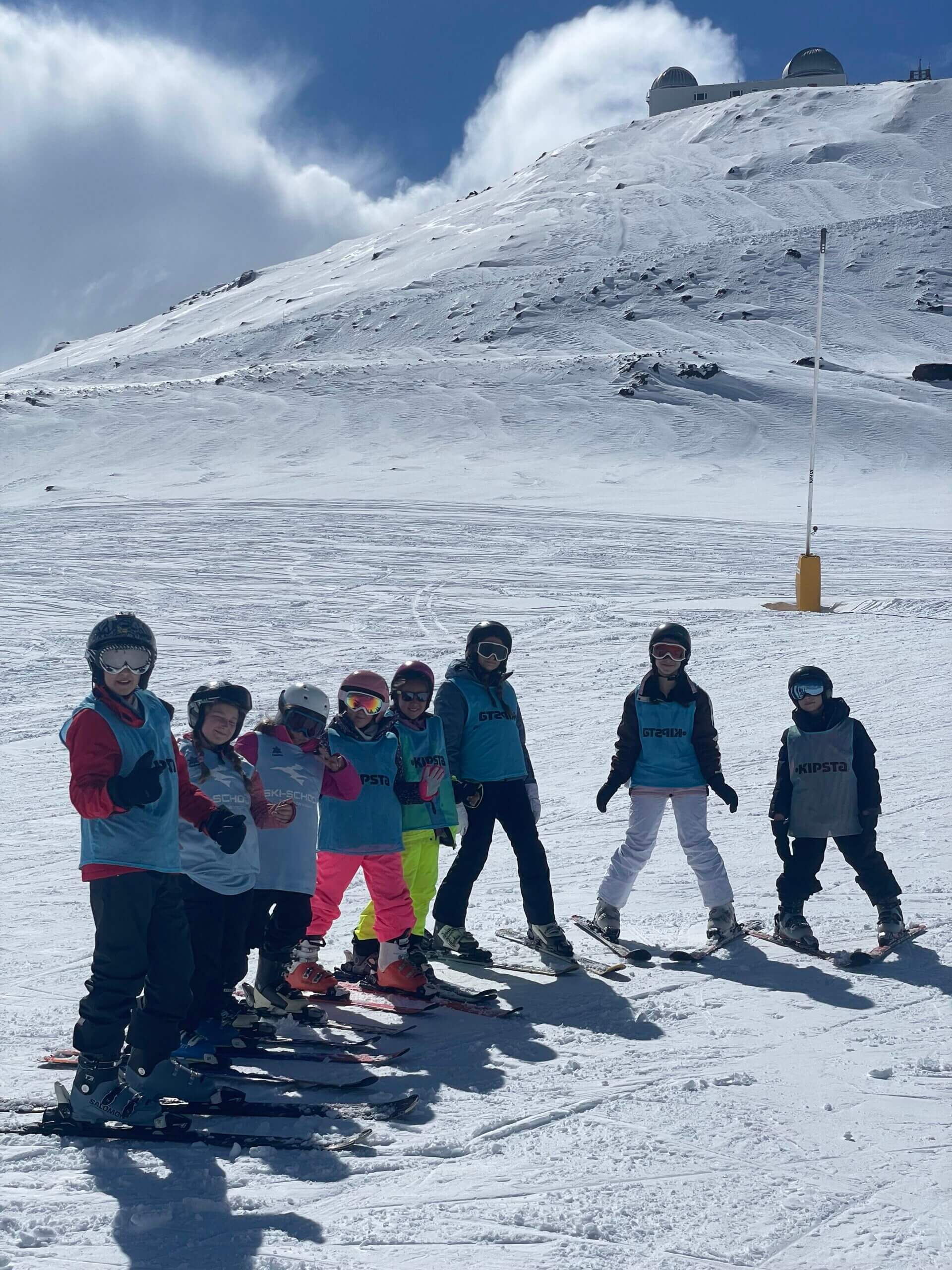 Grupo de niños con petos de Ski School Sierra Nevada durante un curso Ski Kids