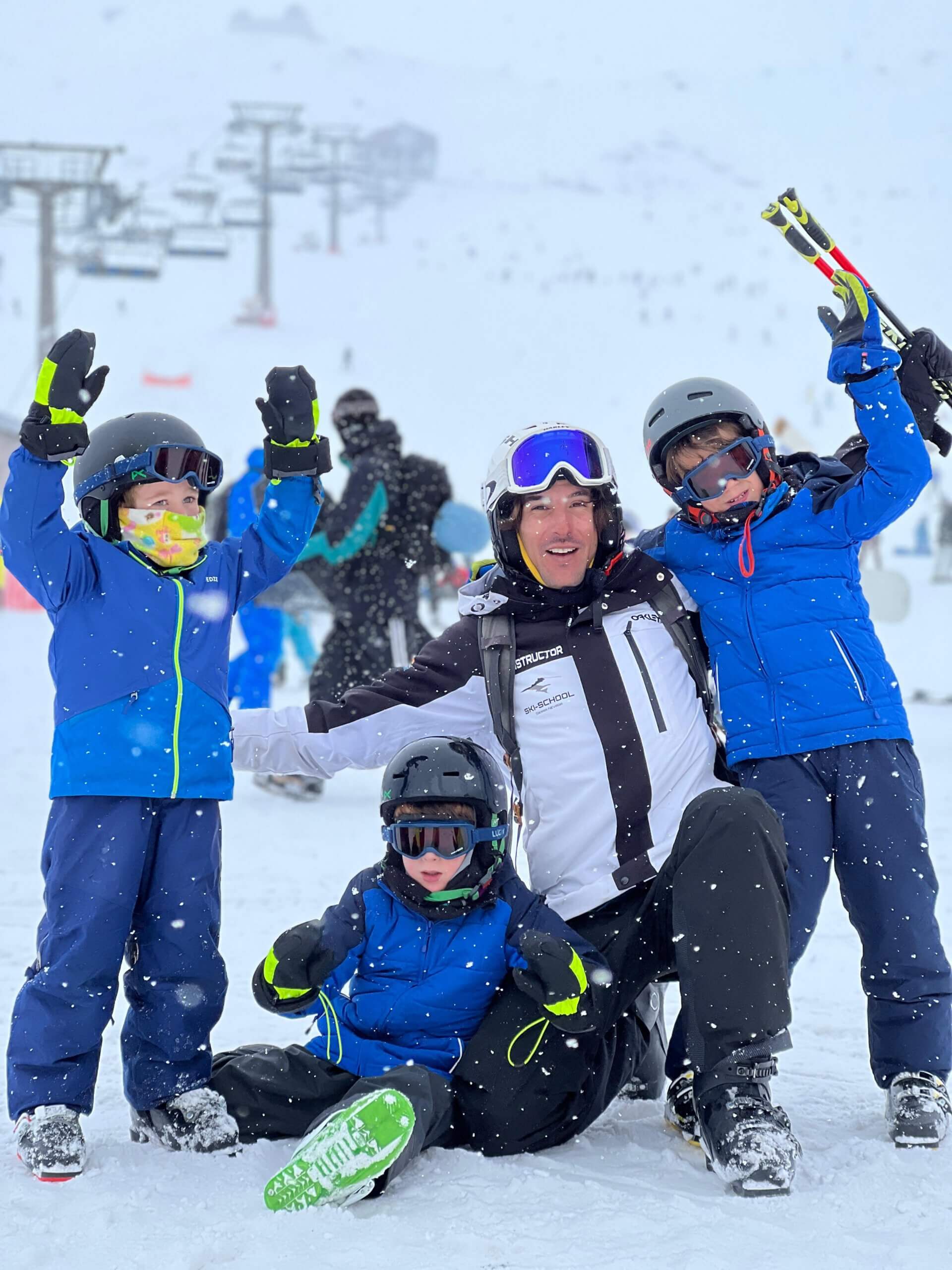 Profesor de Ski School con tres niños sonriendo en la nieve de Sierra Nevada